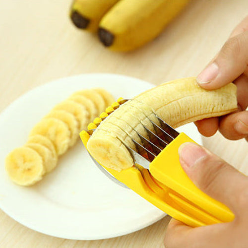 Person using a yellow banana peeler on a banana with a white plate and additional bananas in the background.