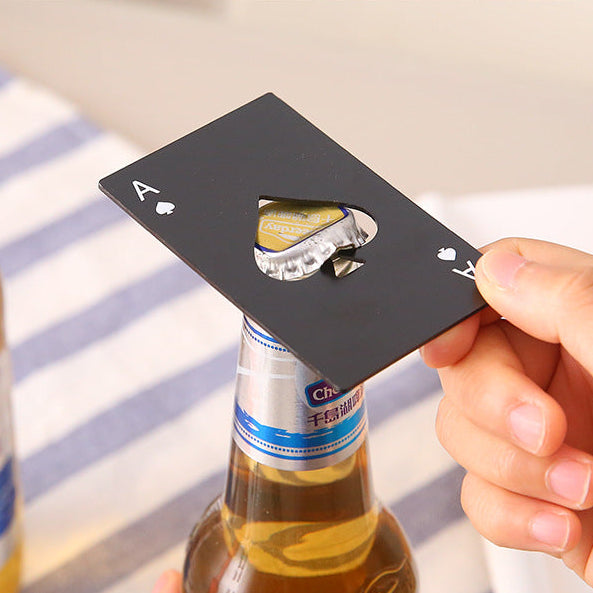 Hand holding a black card-shaped bottle opener with a beer bottle in the background