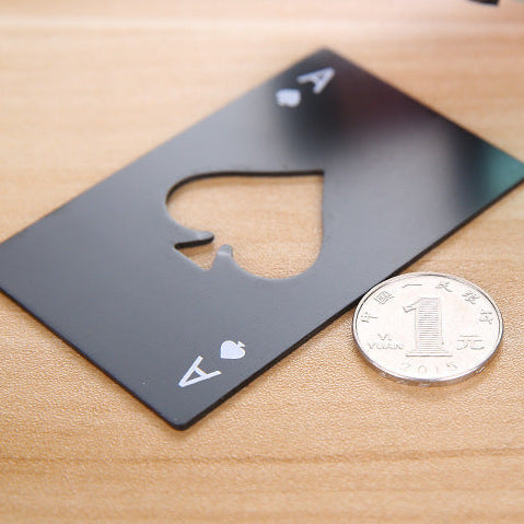 Black card-shaped bottle opener next to a coin on a wooden surface